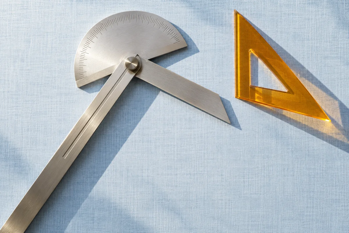 Generated editorial still life of a steel bevel protractor and amber set square on blue linen